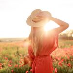 mujer mirando al campo con vestido rojo y sombrero