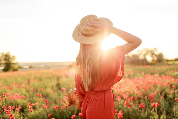 mujer mirando al campo con vestido rojo y sombrero